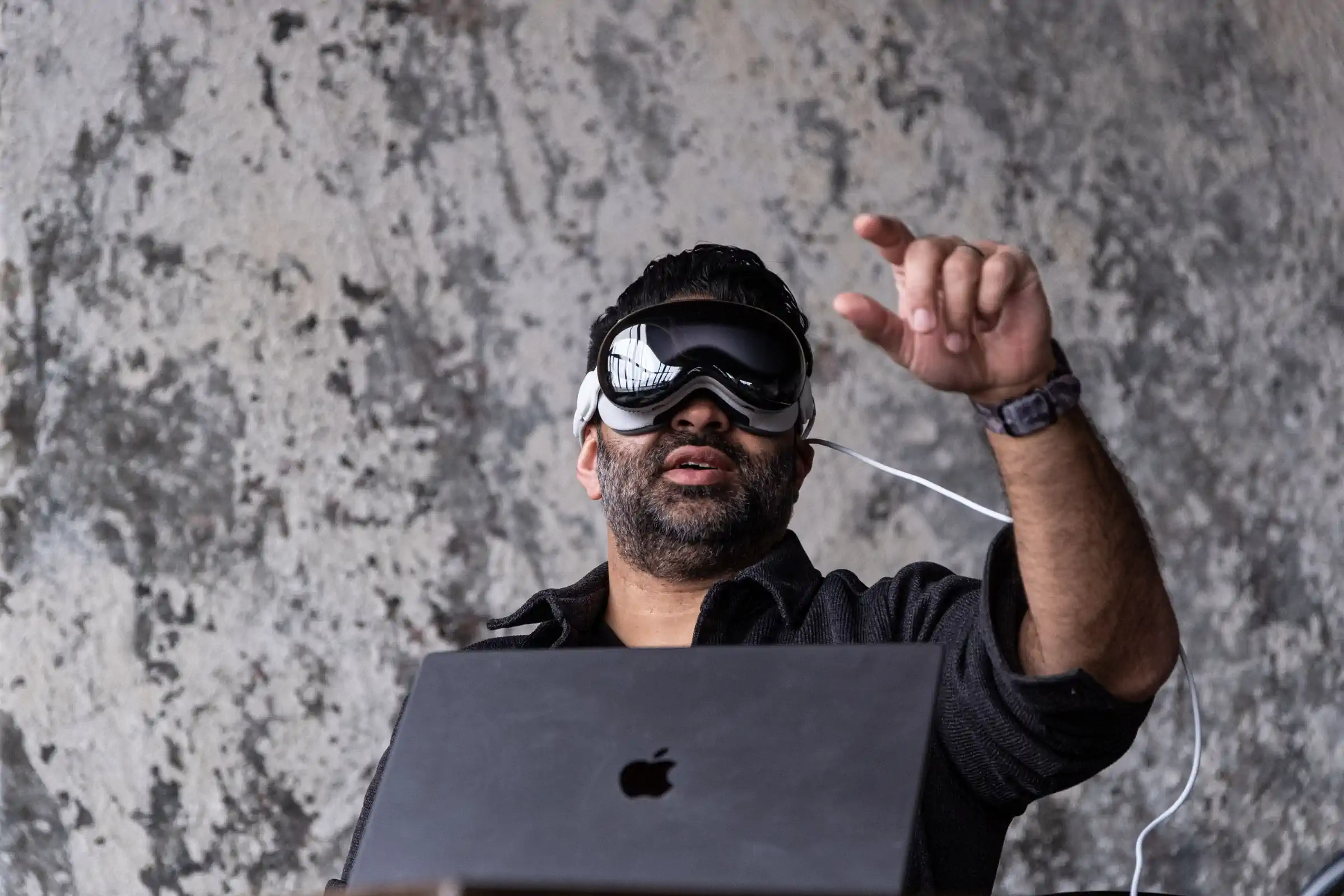 伸出手，触摸你的信仰。Nilay Patel 正伸手触碰空气，同时佩戴了一款名为 Vision Pro 的设备。照片：Vjeran Pavic / The Verge 摄